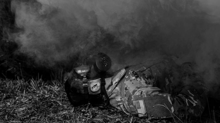 Soldier with gas mask enveloped by yellow cloud of simulated chemical weapon