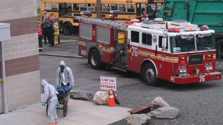 Scene of disaster triage with fire truck, schoolbus and first responders in hazmat suits with patients